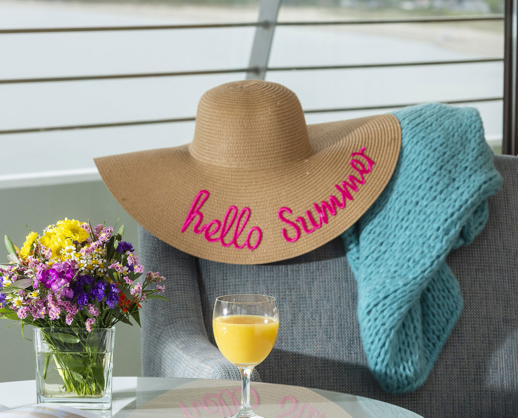 View from the balcony Detail with sun hat, blanket and juice glass by the window overlooking the Baltic Sea