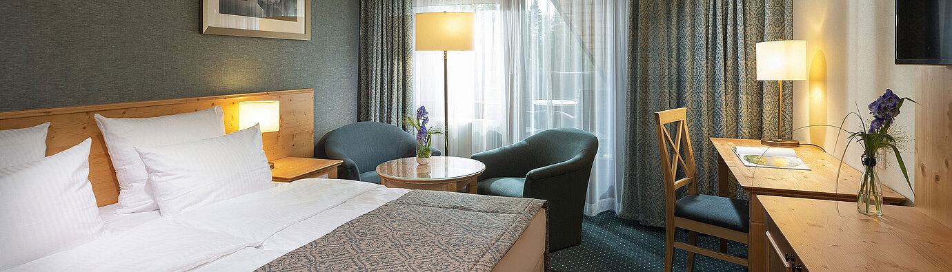 Cosy double room with desk and seating area at Maritim Hotel Titisee