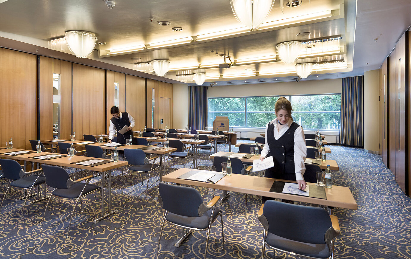 Saal Maritim II classroom style  Staff preparing a conference room at Maritim Hotel Frankfurt with row seating and views of greenery.