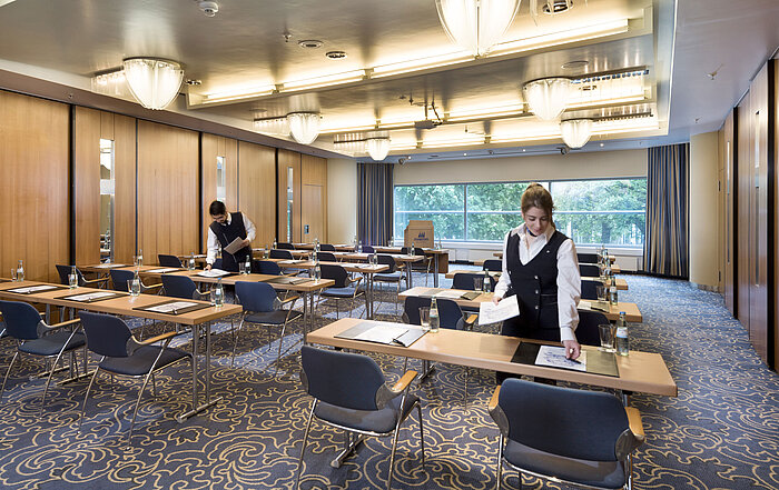 Saal Maritim II classroom style  Staff preparing a conference room at Maritim Hotel Frankfurt with row seating and views of greenery.