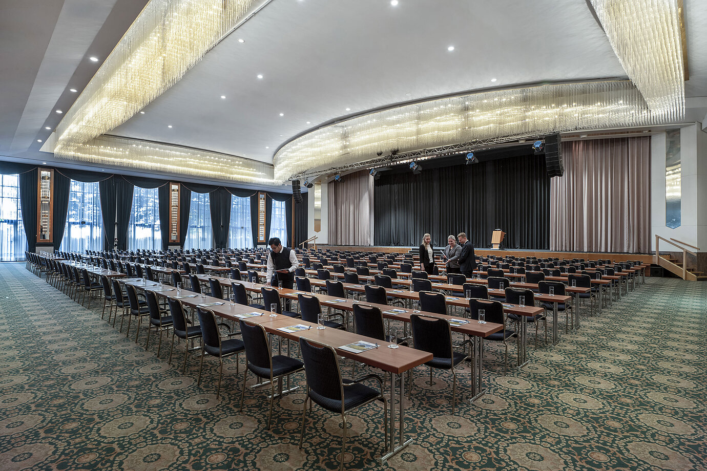 Magnificent hall at the Maritim Hotel Magdeburg with a stage, row seating, and luxurious chandelier.