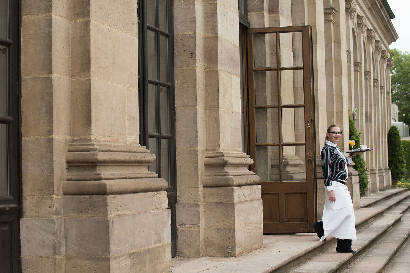 Friendly waitress serving breakfast with freshly squeezed orange juice on the terrace of Maritim Hotel Fulda.