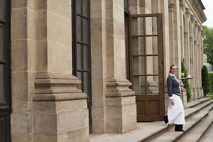 Friendly waitress serving breakfast with freshly squeezed orange juice on the terrace of Maritim Hotel Fulda.