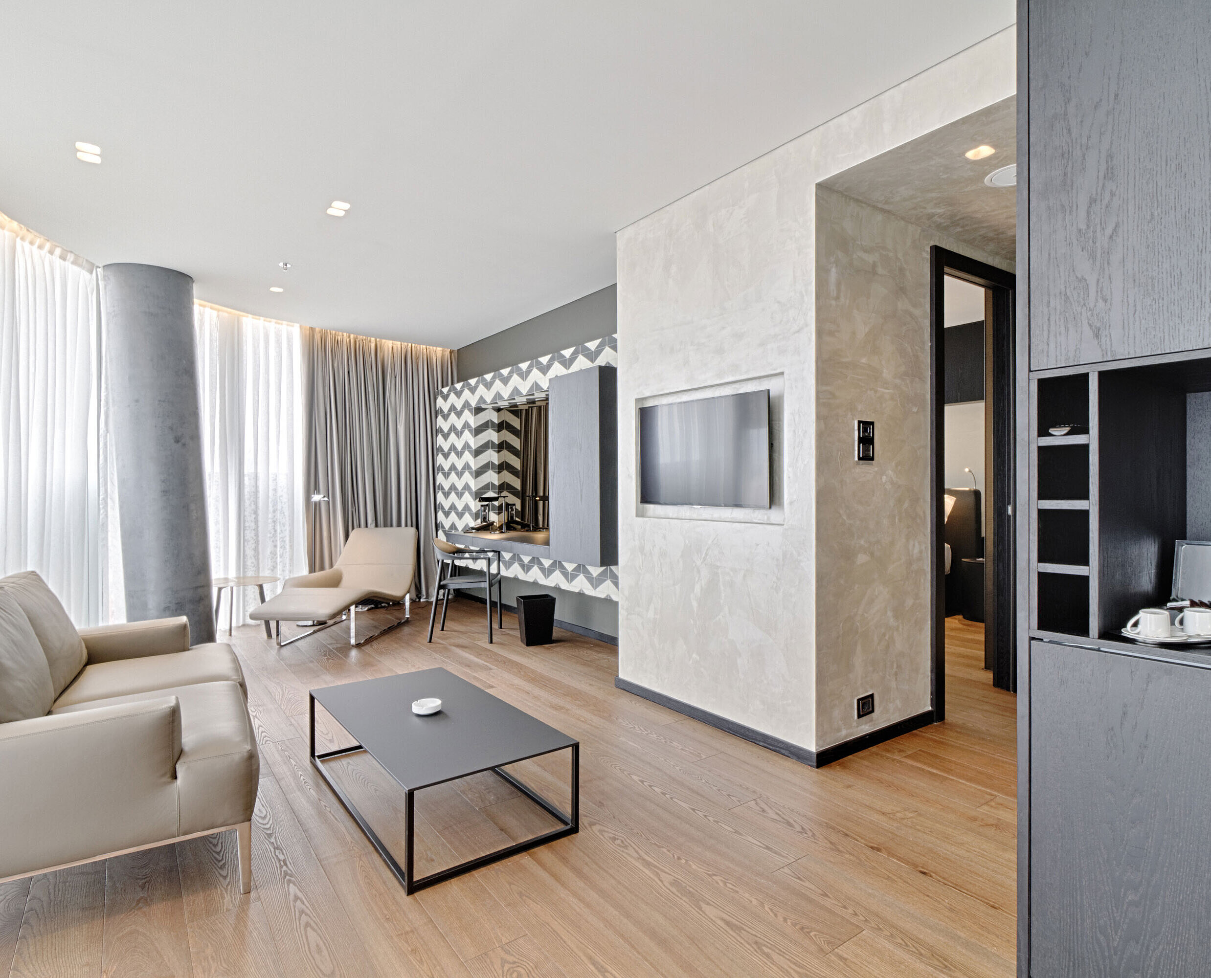 Suite Lounge with sofa, TV, designer mirror and lounger at Maritim Hotel Plaza Tirana with natural light
