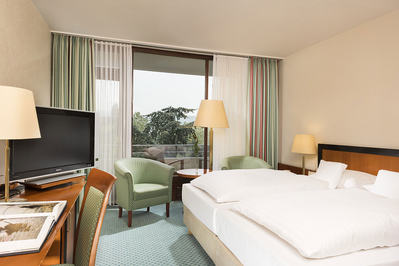 Bright hotel room at Maritim Hotel Bad Salzuflen with double bed, seating area and balcony access