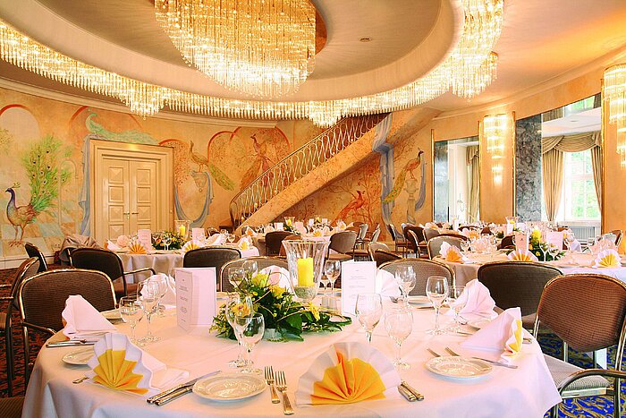 Elegant banquet hall with wall paintings, chandeliers and festively set tables