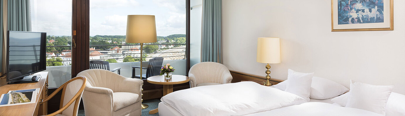 Bright double room at Maritim Hotel Travemünde with balcony and view over rooftops and water