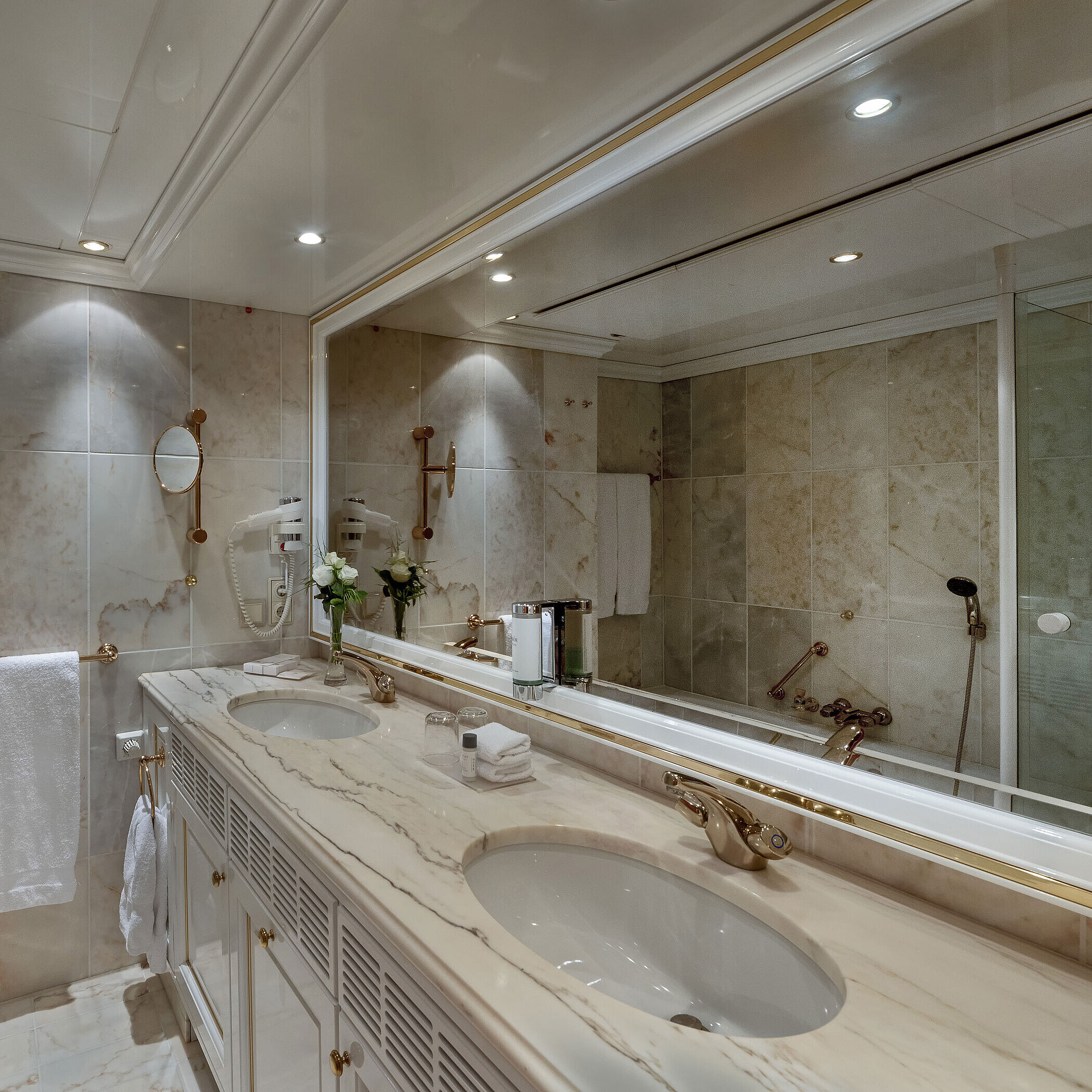 Bath Marble bathroom in the Maritim Airport Hotel Hannover with double vanity, mirror, and bathtub.