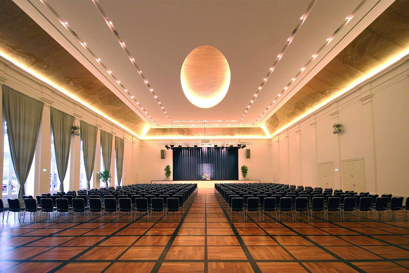 Elegant banquet hall at Maritim Hotel Fulda with a stage, stylish lighting, and seating for events.