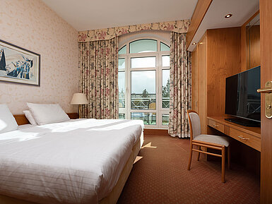 Junior Suite with bright bedroom, double bed, balcony access, large TV and a cosy interior.
