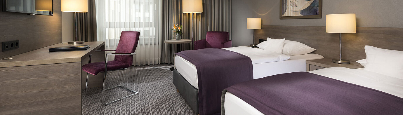 Modern twin room at Maritim Hotel Königswinter with two beds, desk, and stylish decor.