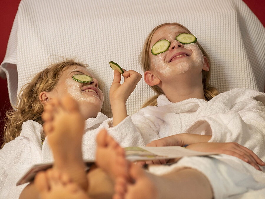 Two girls with facial masks and cucumber slices relax at the Maritim Hotel Spa, enjoying their treatment.