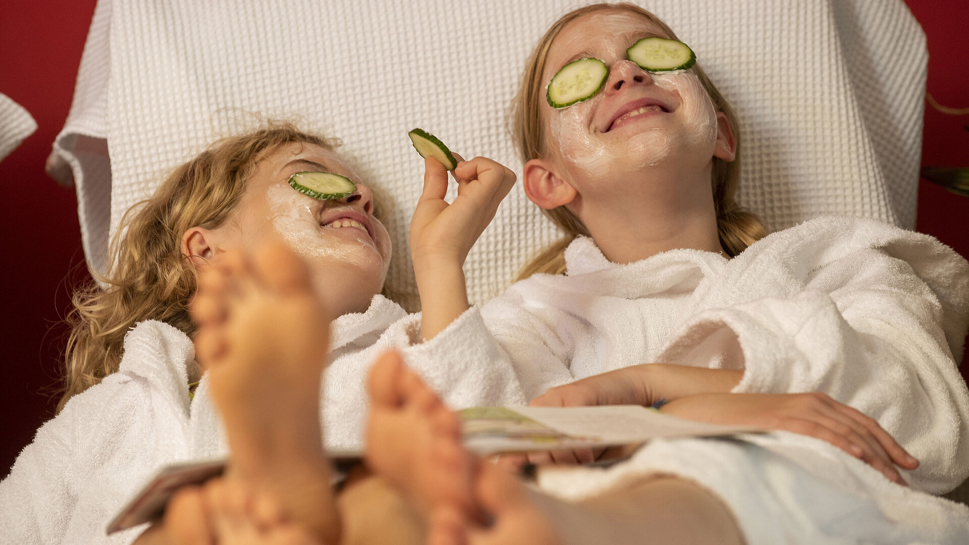 Two girls with facial masks and cucumber slices relax at the Maritim Hotel Spa, enjoying their treatment.