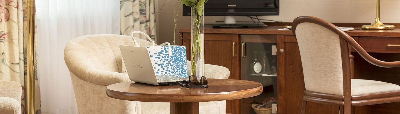 Cosy seating area with roses, laptop and TV in the room of Maritim Hotel Bad Wildungen