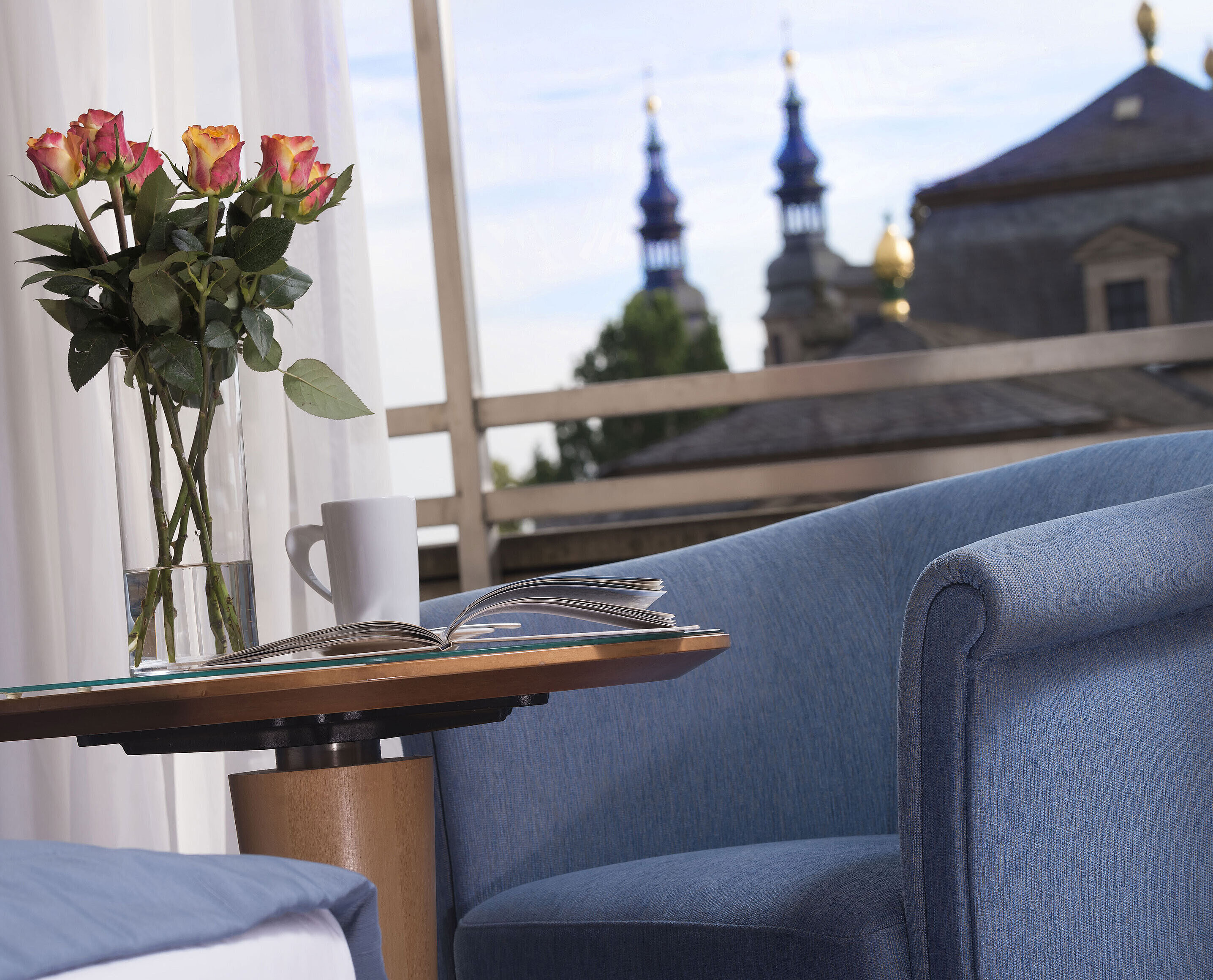 Detail of the hotel room Elegant room detail at Maritim Hotel Fulda with blue seating, roses, and a view of the baroque towers of Fulda.