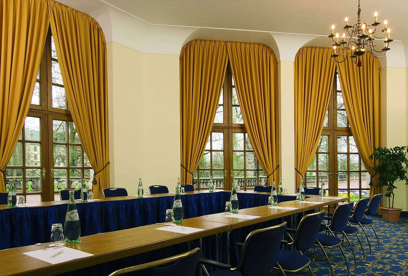 Stylish meeting room with large windows, golden curtains, and chandelier at Maritim Hotel Fulda.