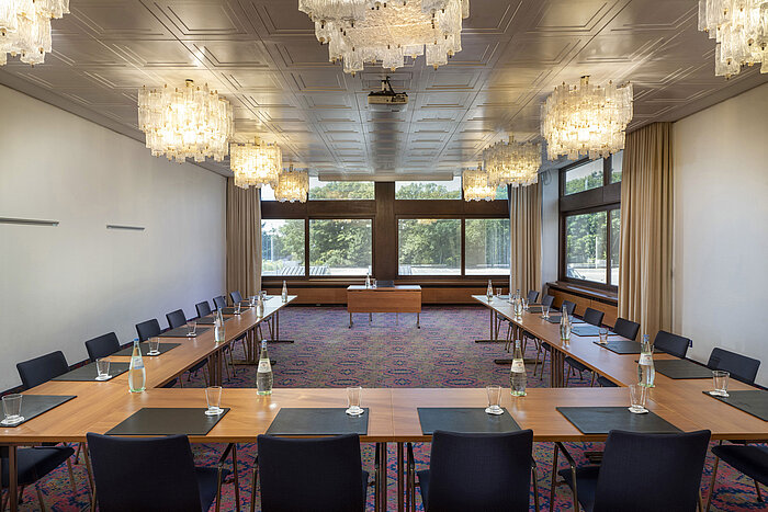 U-shaped meeting room with elegant chandeliers and large windows at Maritim Hotel Travemünde