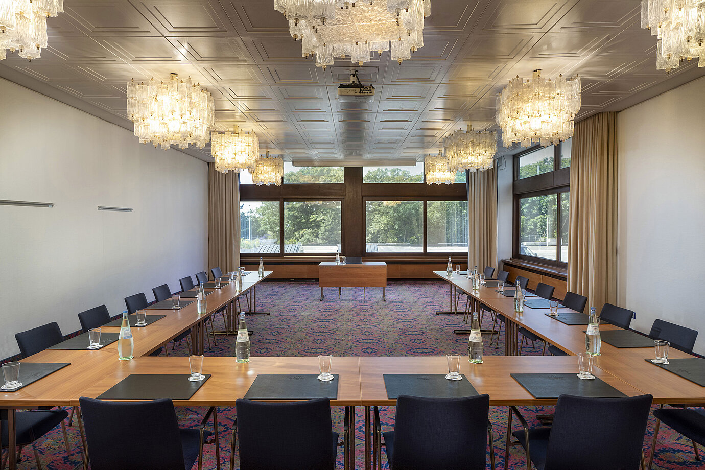 U-shaped meeting room with elegant chandeliers and large windows at Maritim Hotel Travemünde