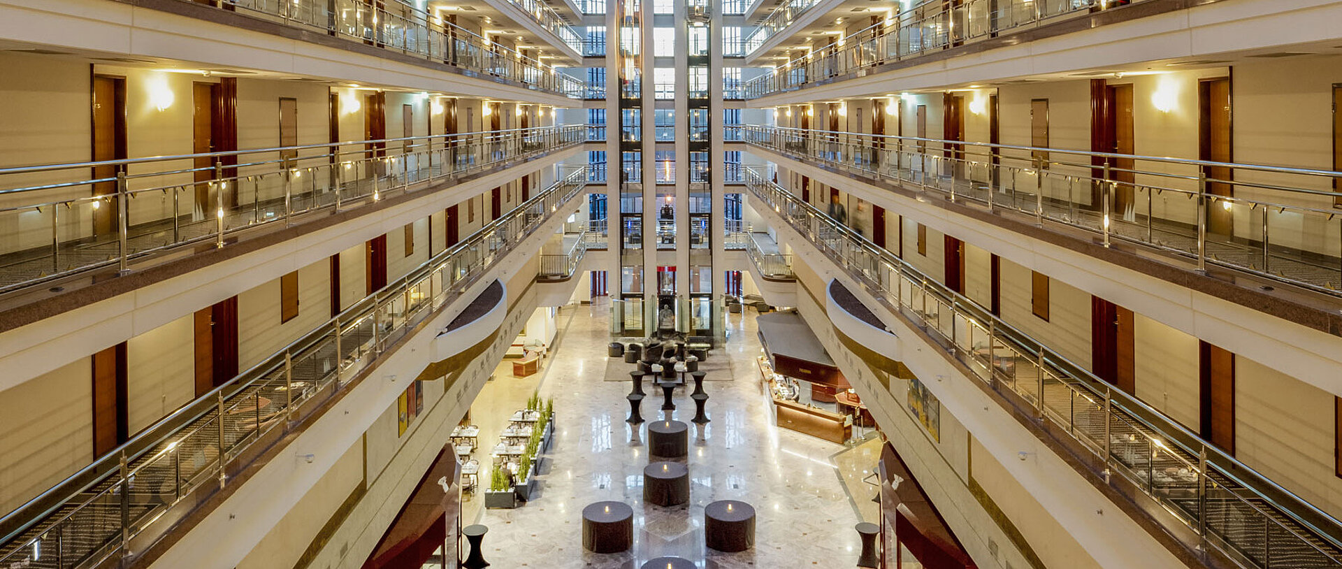 Impressive hotel lobby with glass ceiling, multiple floors, and seating areas, creating a spacious and elegant ambiance