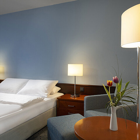 Comfortable single room with queen-size bed, modern furniture, and ambient lighting at the Maritim Hotel Darmstadt.