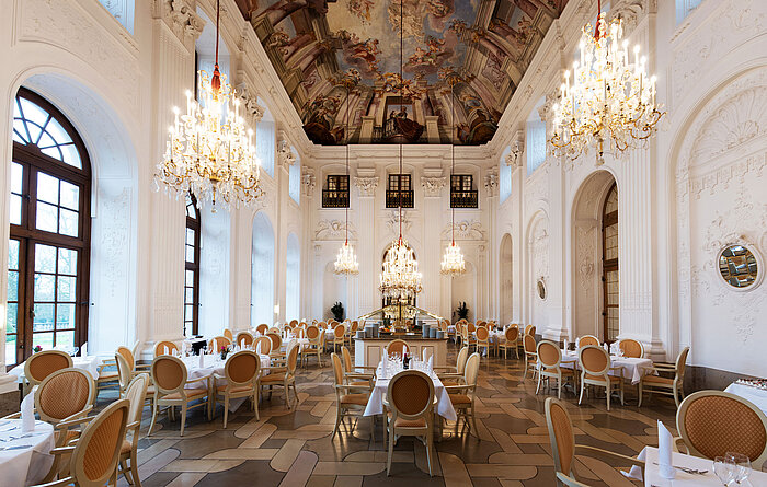 Elegant Apollo Hall at Maritim Hotel Fulda with chandeliers, fresco ceiling, and stylishly set tables.
