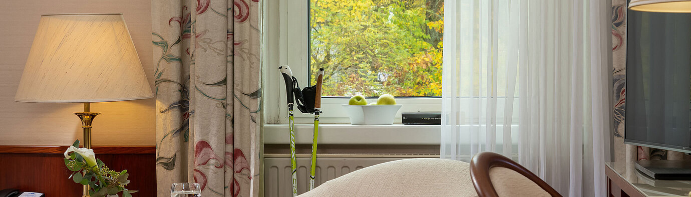 Classic single room Seating area in the classic single room with armchair, table, lamp and window view at Maritim Hotel Bad Wildungen.