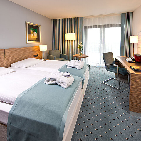 Superior room at Maritim Hotel Darmstadt featuring stylish design, desk, cozy seating area, and double bed with bathrobes.