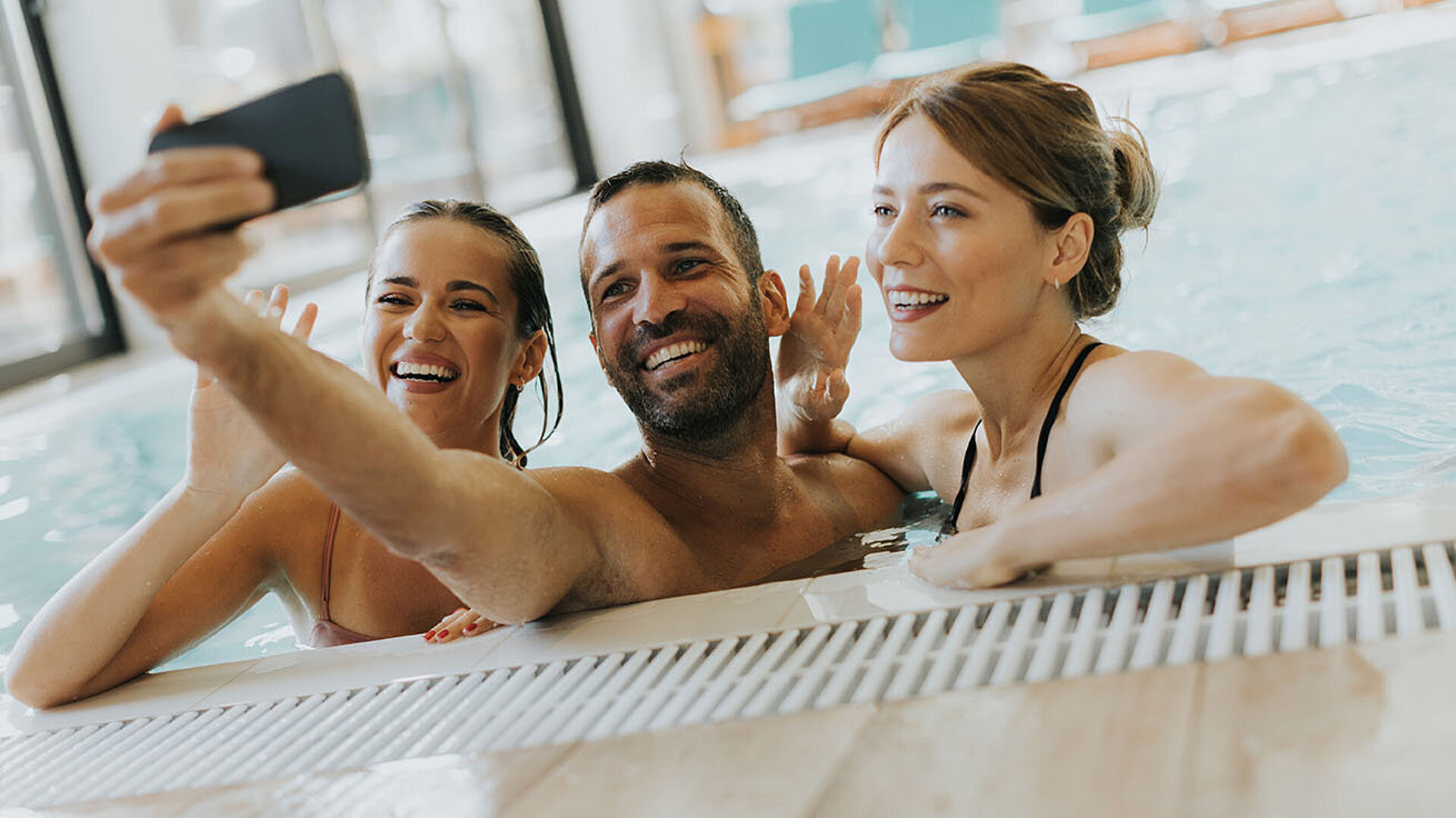 Three friends take a selfie in the hotel pool enjoying time together