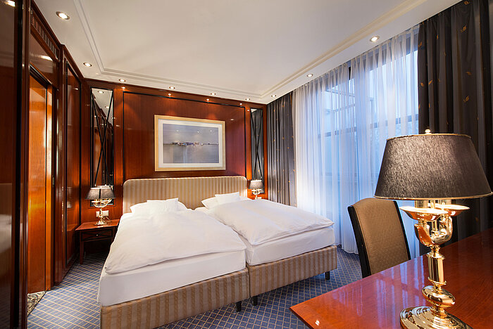 Elegant suite at Maritim Hotel Fulda with a luxurious double bed, stylish wood elements, and cozy lighting.