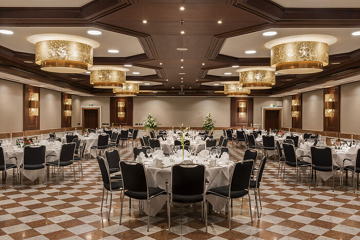 Elegant banquet hall at Maritim Hotel Königswinter with round tables, stylish decor, and chandeliers.