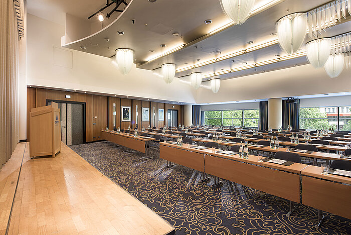Saal Maritim III classroom style   Conference room with stage and panoramic windows at Maritim Hotel Frankfurt. Row seating and modern design.