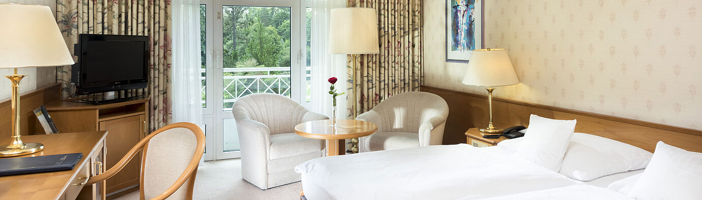 Bright double room with balcony view and seating area at Maritim Hotel Bad Wildungen