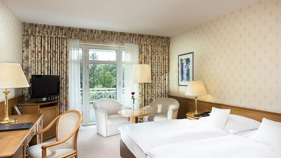 Bright double room with balcony view and seating area at Maritim Hotel Bad Wildungen