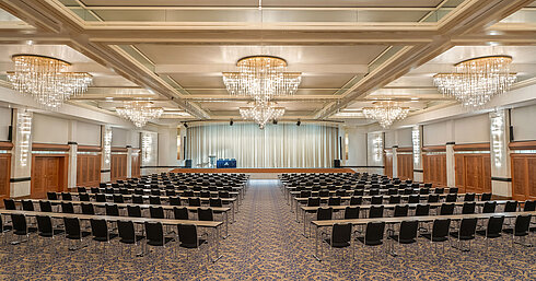 Fürst-von-Metternich-Saal Salle Fürst-von-Metternich avec grande scène, rangées de sièges, lustres élégants et ambiance lumineuse.