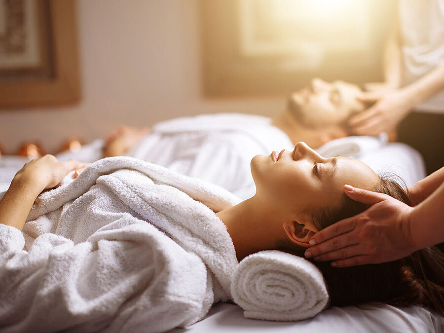 Couple enjoying relaxing head and neck massage at the spa in white bathrobes