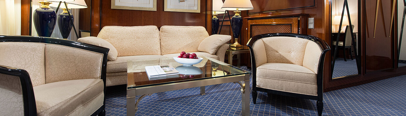 Elegant living area of a suite at Maritim Hotel Fulda with stylish furniture, glass coffee table, and cozy lighting.