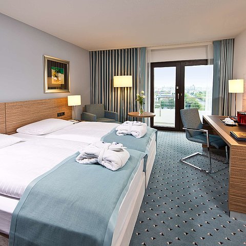 Superior room at Maritim Hotel Darmstadt featuring stylish design, desk, cozy seating area, and double bed with bathrobes.