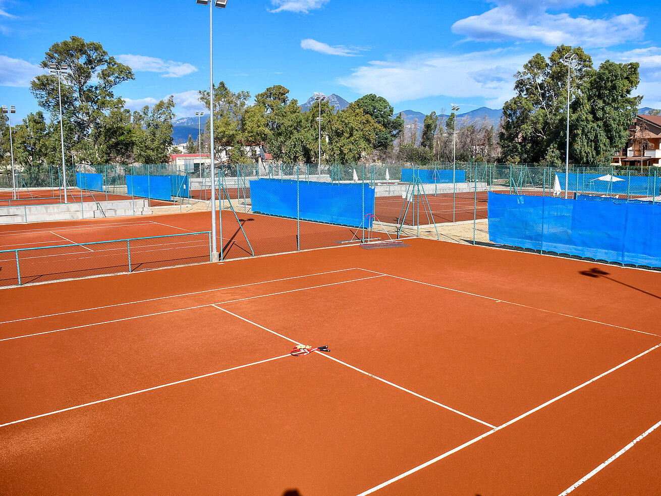Tennis court Red clay tennis courts at Maritim Resort Calabria under blue sky for sporty holiday activities