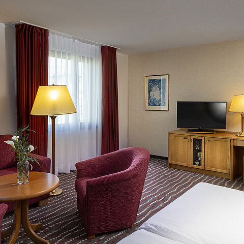 Comfortable studio room at the Maritim Hotel Magdeburg with seating area, desk, and modern TV.