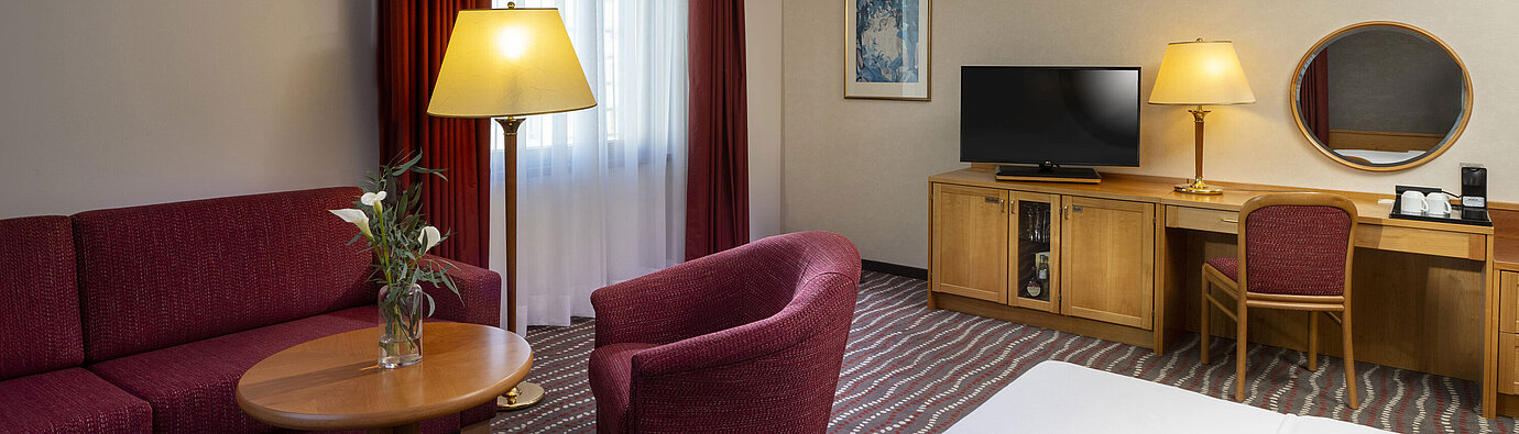 Comfortable studio room at the Maritim Hotel Magdeburg with seating area, desk, and modern TV.