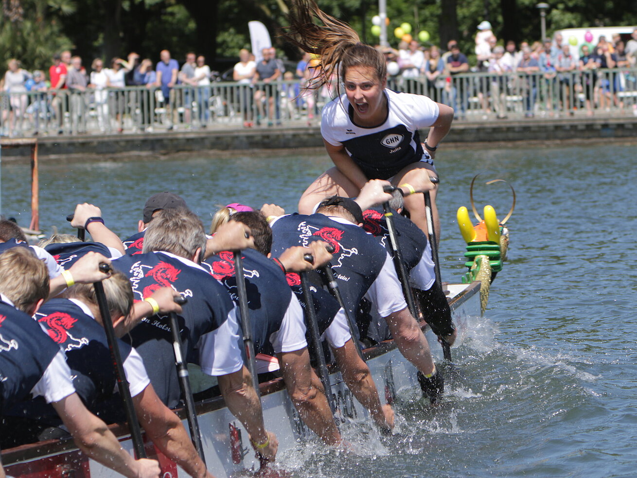 Dragon boat team racing on a river with cheering steerswoman