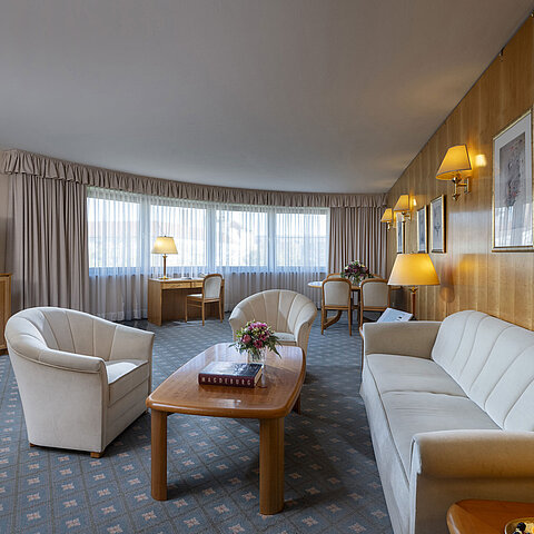 Spacious living room of a suite at the Maritim Hotel Magdeburg with elegant furnishings, seating area, and workspace.