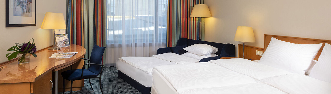 Classic Family room Classic family room at Maritim Hotel Frankfurt with double bed, sofa bed, desk, and colorful curtains.