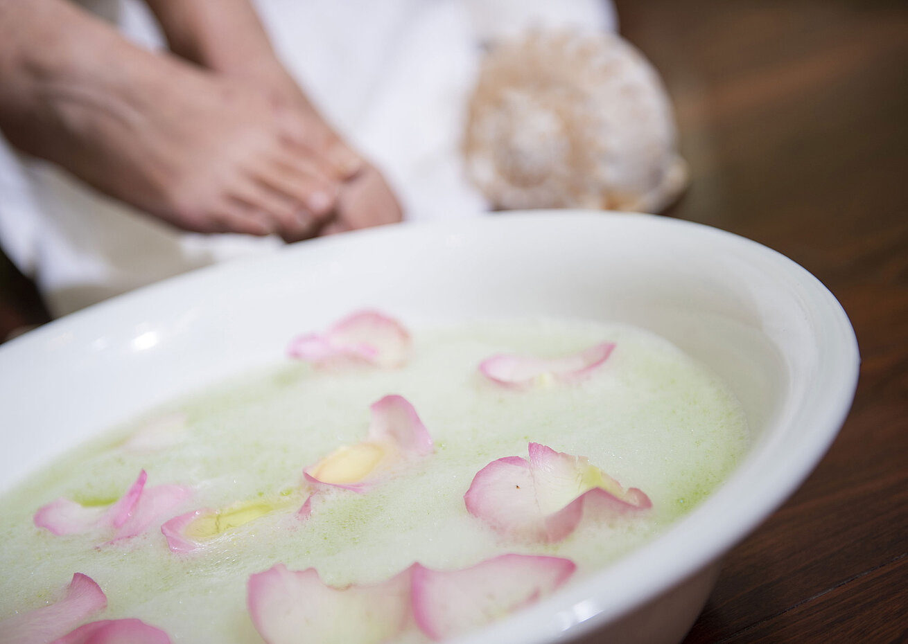 Foot bath with rose petals in a bowl during a spa treatment at the Maritim Hotel for soothing relaxation and care.