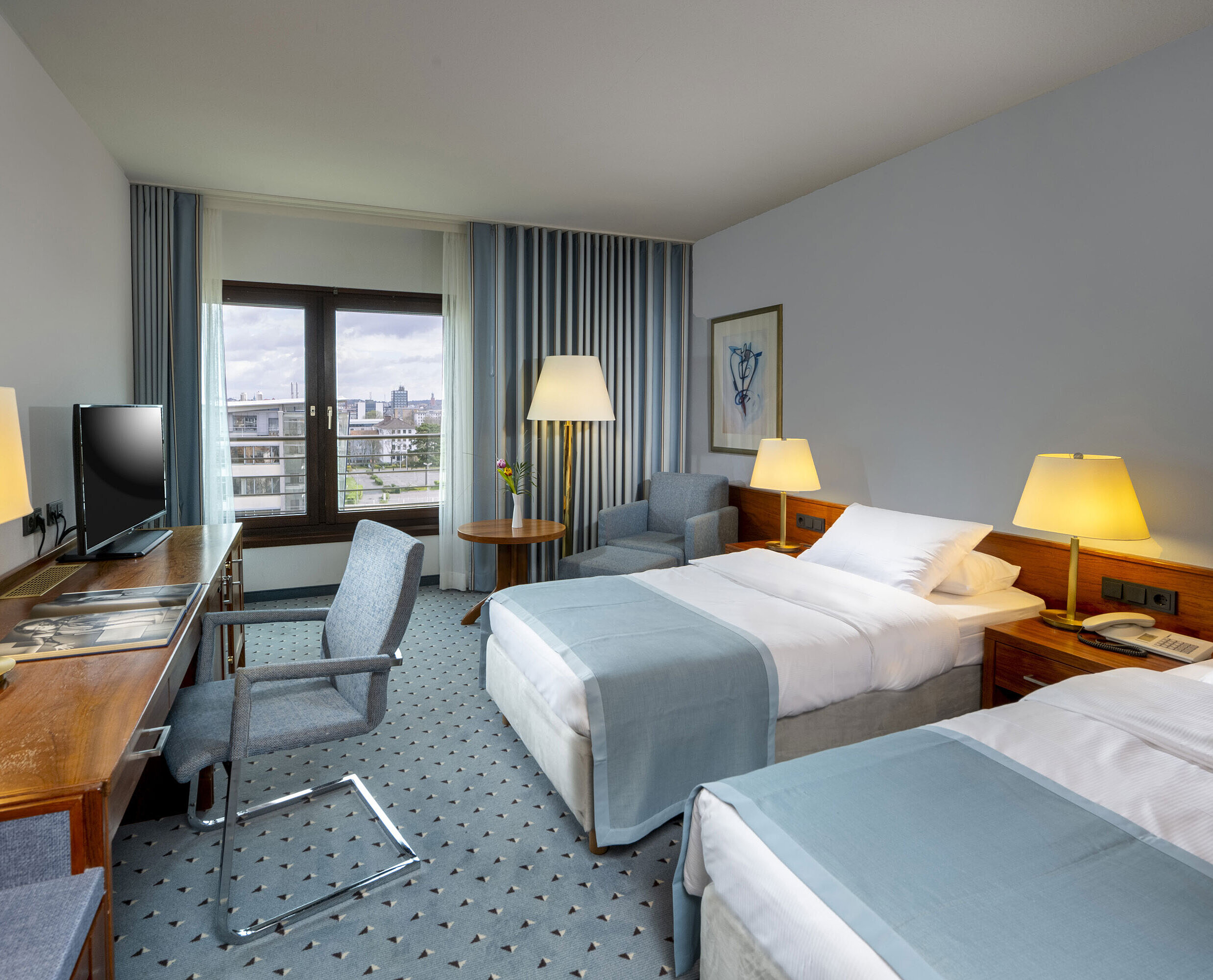 Comfort room twin Comfort twin room at Maritim Hotel Darmstadt with desk, two single beds, and panoramic window with city view.