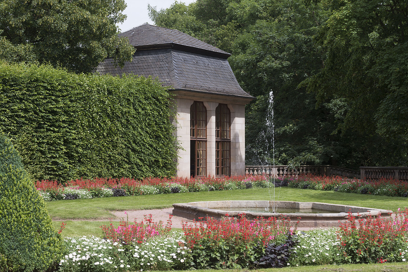 Historic pavilion in the blooming garden of Maritim Hotel Fulda with water feature and fountain.