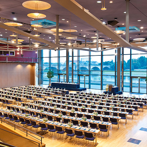 Large conference hall in Maritim Hotel Dresden with rows of blue chairs and a view of the Elbe River.