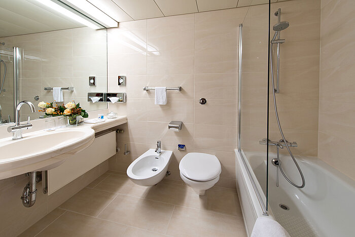 Bathroom  Bright, elegant bathroom with bathtub, shower, sink, and mirror at Maritim Hotel Hannover.
