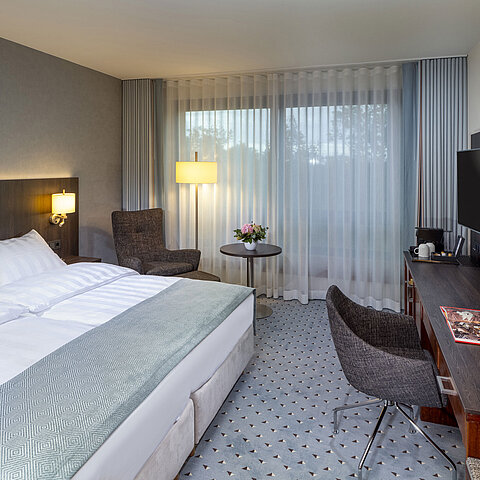 Modern superior double room at Maritim Hotel Bremen with seating area, desk, and large window for natural light.