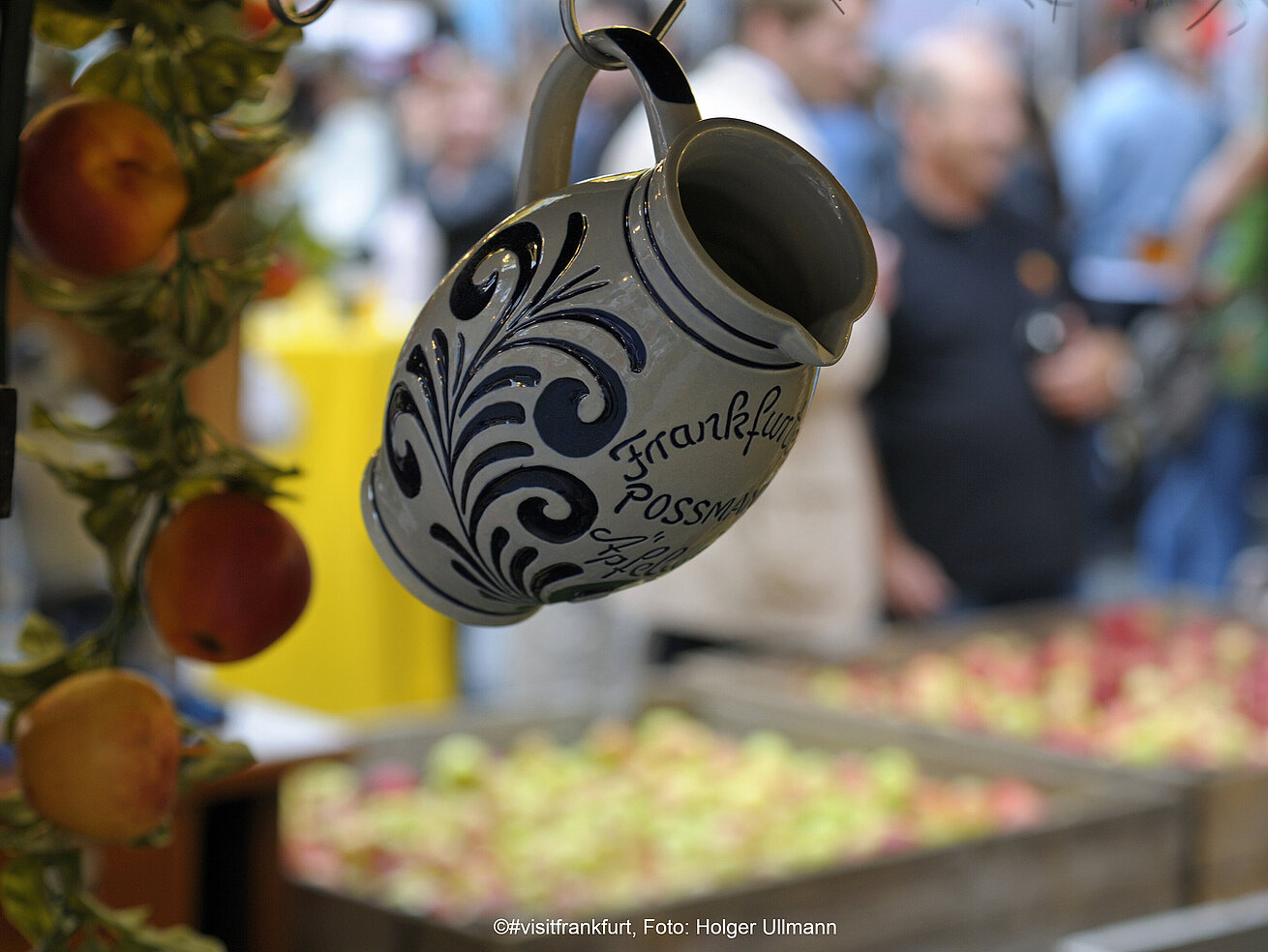 Traditional Frankfurt cider mug at a weekly market with blurred stalls in the background
